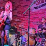 Candid shot of Champagne Lipsmack performing at Soulbelly BBQ against a pink background